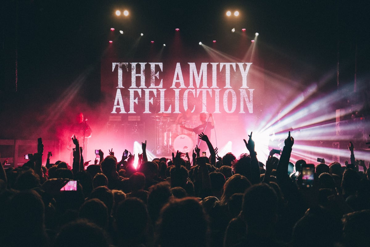 The Amity Affliction performing beneath its tour lettering as the crowd raises its hands